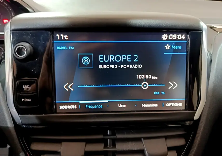 Écran tactile central du tableau de bord du Peugeot 208 blanc, affichant la radio Europe 2 à 103,5 MHz.