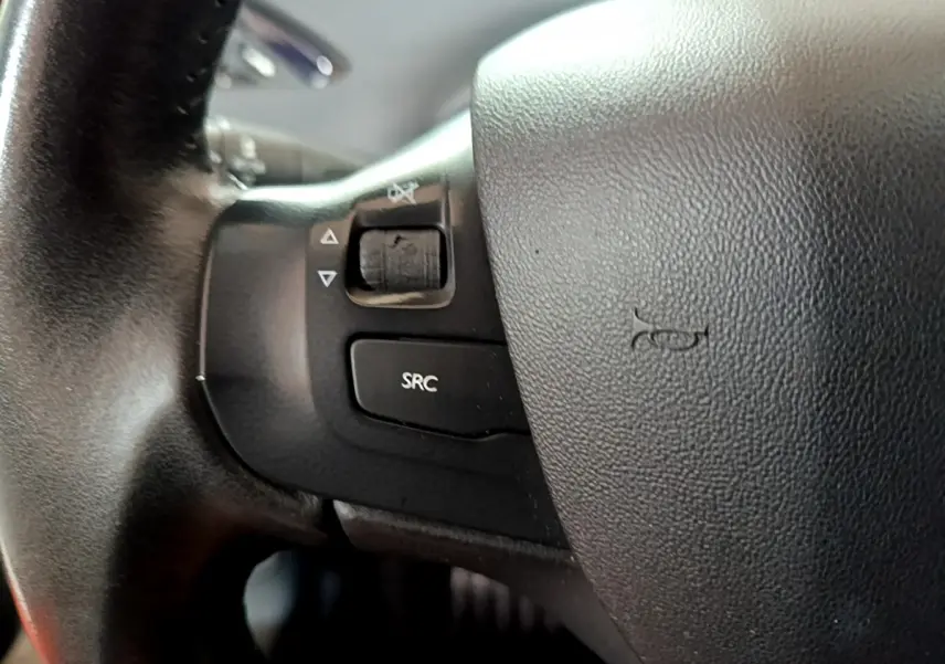 Gros plan sur les commandes gauche du volant cuir noir d'une Peugeot 208 Puretech 82 Signature blanche de 2018.