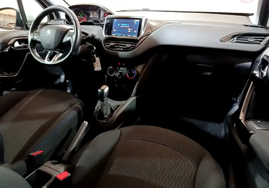 Intérieur de la Peugeot 208 Puretech 82 Signature 2018, vue côté conducteur, tableau de bord avec écran tactile et volant cuir.