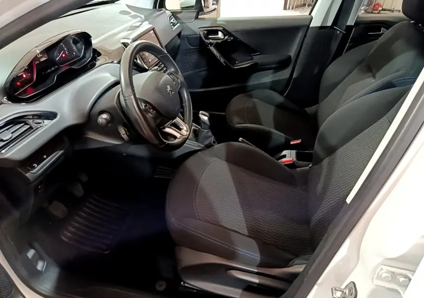 Intérieur avant droit de la Peugeot 208 blanche, volant cuir, tableau de bord numérique et sièges tissu noirs.