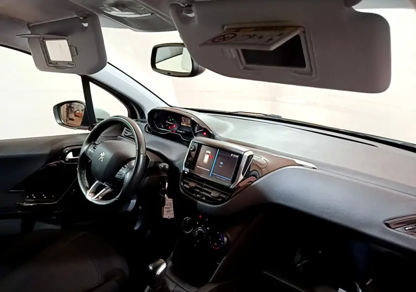 Intérieur de la Peugeot 208 Puretech 82 Signature 2018, vue côté conducteur, tableau de bord avec écran tactile et volant cuir.