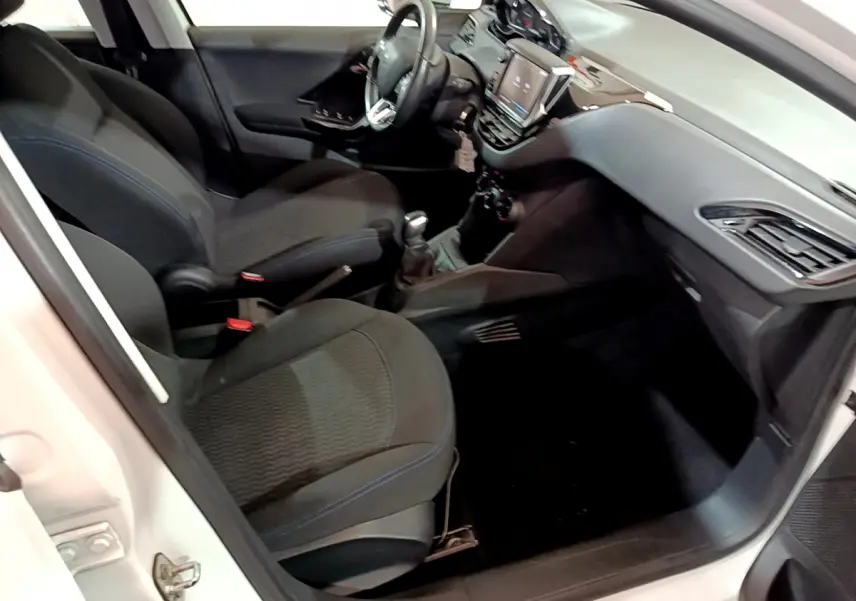 Intérieur de la Peugeot 208 Puretech 82 Signature 2018, vue côté droit, sièges noirs et tableau de bord moderne.