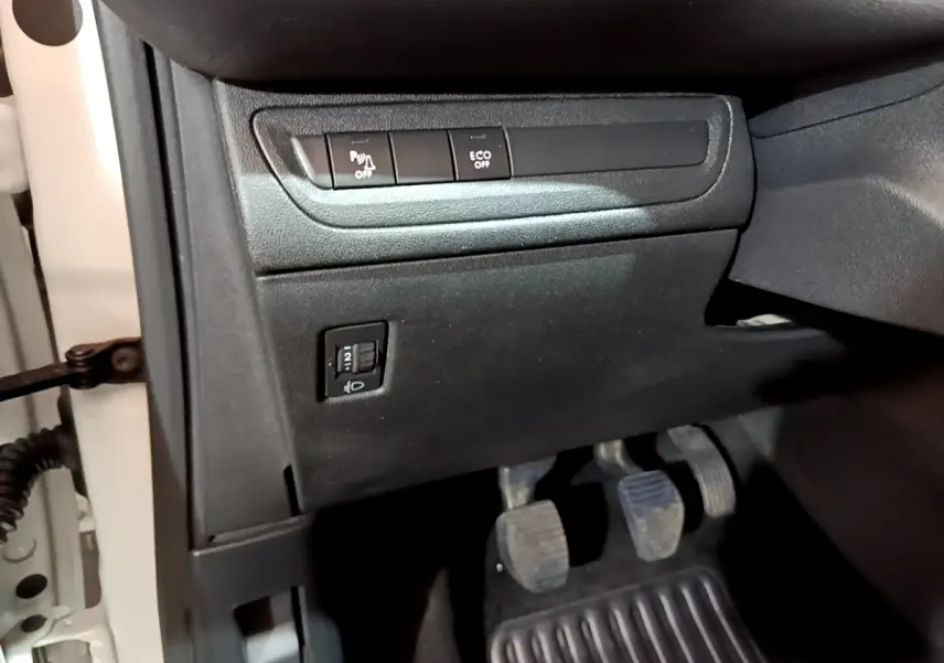 Vue du tableau de bord côté gauche avec commandes de régulation phares et désactivation capteurs sur Peugeot 208 blanc