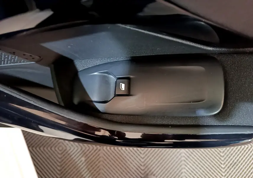 Gros plan sur le bouton d'ouverture de coffre côté conducteur de la Peugeot 208 Puretech 82 Signature blanche.