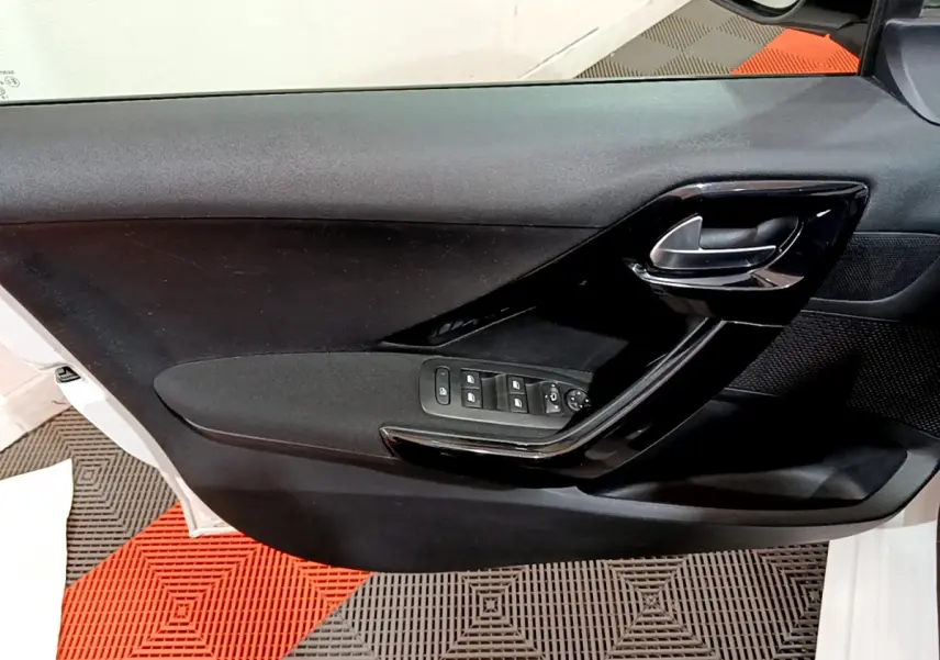 Vue côté gauche de la porte avant blanche d'une Peugeot 208 2018 avec commandes électriques et poignée noire brillante.