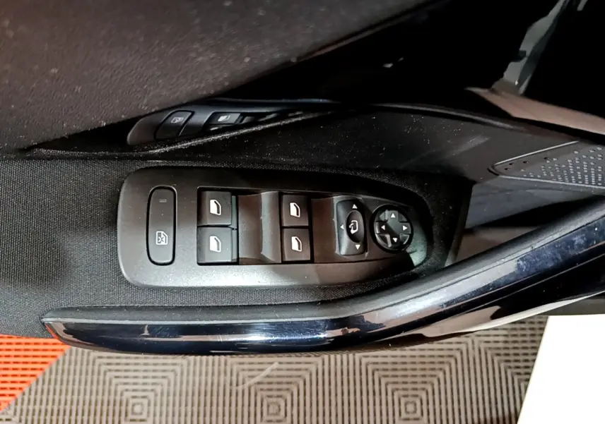 Gros plan sur les commandes des vitres électriques et rétroviseurs côté gauche d'une Peugeot 208 blanche.