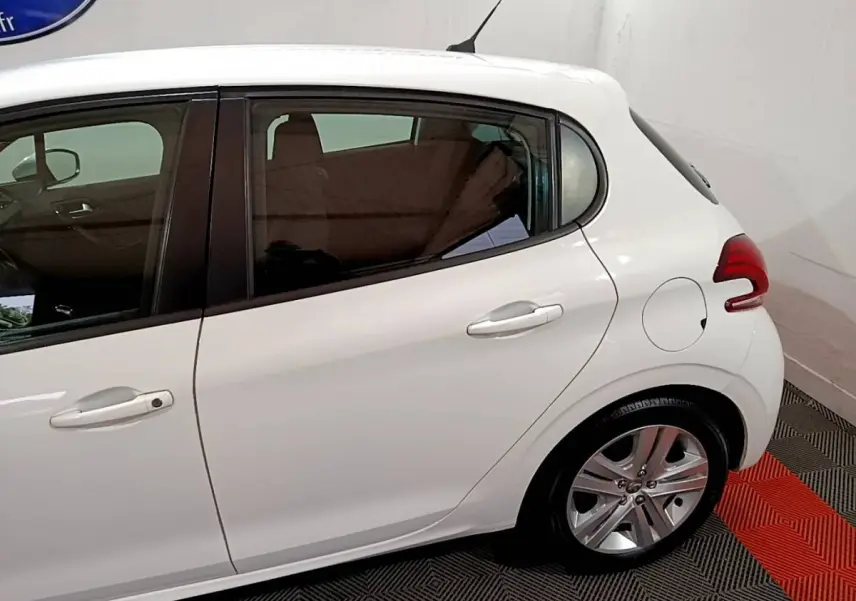 Vue latérale droite d'une Peugeot 208 blanche, mettant en valeur la porte arrière et la roue arrière en alliage.