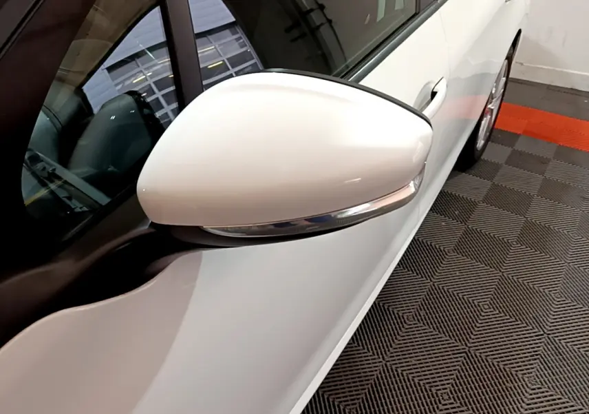 Gros plan sur le rétroviseur droit blanc d'une Peugeot 208 Puretech 82 Signature 2018, vue côté conducteur.
