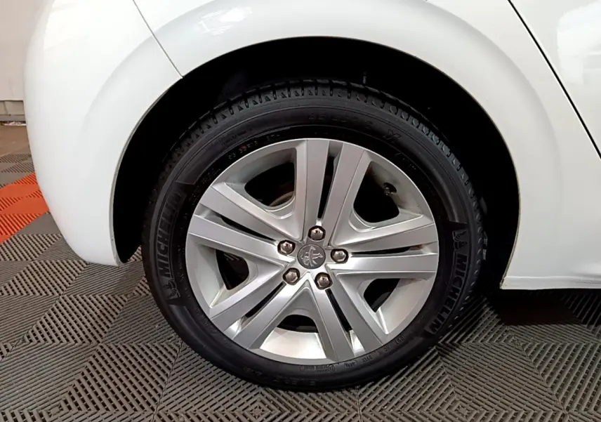 Gros plan sur la roue avant droite blanche d'une Peugeot 208 Puretech 82 Signature avec jante alliage et pneu Michelin.