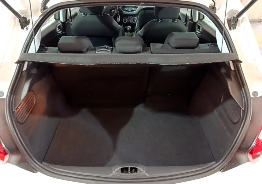 Coffre ouvert vu de l'arrière d'une Peugeot 208 blanche, montrant l'espace de chargement et les sièges arrière.