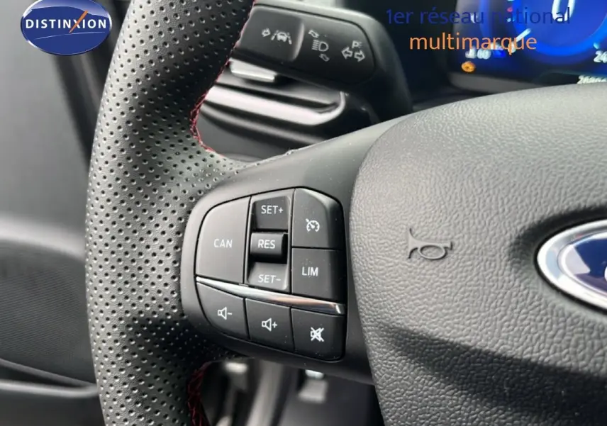 Gros plan sur le volant perforé avec commandes intégrées du Ford Puma gris Magnetic Metal, version hybride 2024.