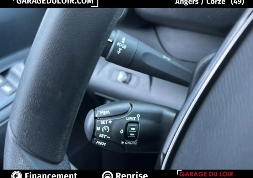 Gros plan sur les commandes de régulateur de vitesse au volant d’un Peugeot Rifter bleu 2024, version Allure.