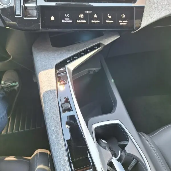 Vue intérieure du poste de conduite du Peugeot 3008 Hybrid 136 e-DCS6 Allure 2025, avec console centrale en tissu gris et écran tactile.