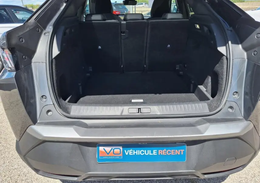 Coffre ouvert vu de l’arrière d’un Peugeot 3008 gris foncé, montrant l’espace de chargement vide et les sièges arrière.