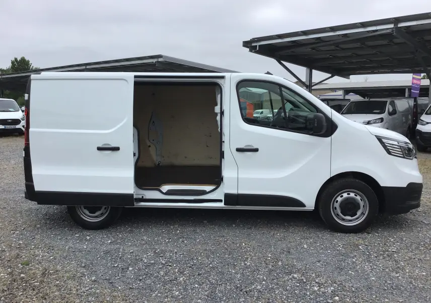 Vue de profil côté gauche d’un Renault Trafic Fourgon blanc 2024 avec porte latérale coulissante ouverte montrant l’intérieur vide.