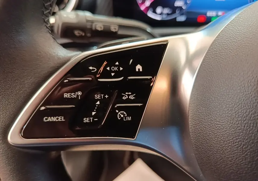 Gros plan sur les commandes du volant côté gauche d'une Mercedes Classe A 250 e Business Line noire, 2023.