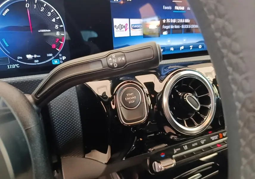 Gros plan intérieur sur le tableau de bord noir brillant de la Mercedes Classe A 250 e, avec bouton start/stop et écran tactile.