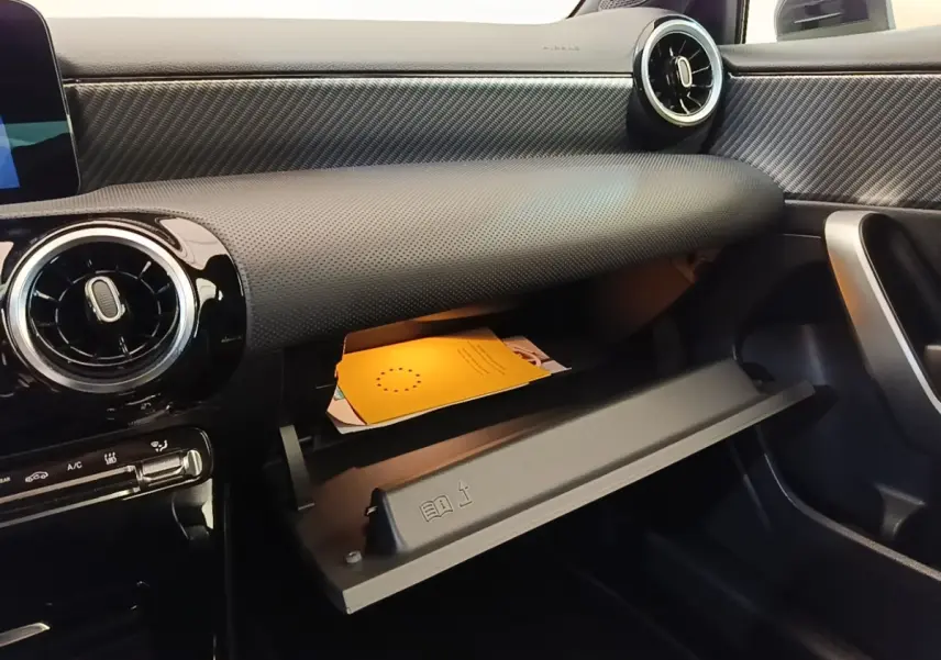Intérieur de la Mercedes Classe A 250 e Business Line 2023, vue côté passager sur la boîte à gants ouverte et tableau de bord noir texturé.