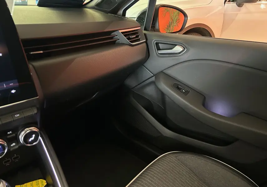 Intérieur côté passager de la Renault Clio V blanc nacré, montrant la portière et la partie basse du tableau de bord.