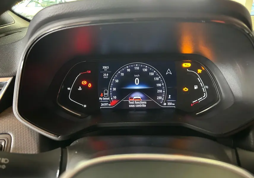 Tableau de bord numérique de Renault Clio V blanc nacré, affichant vitesse zéro et témoins d'alerte allumés.