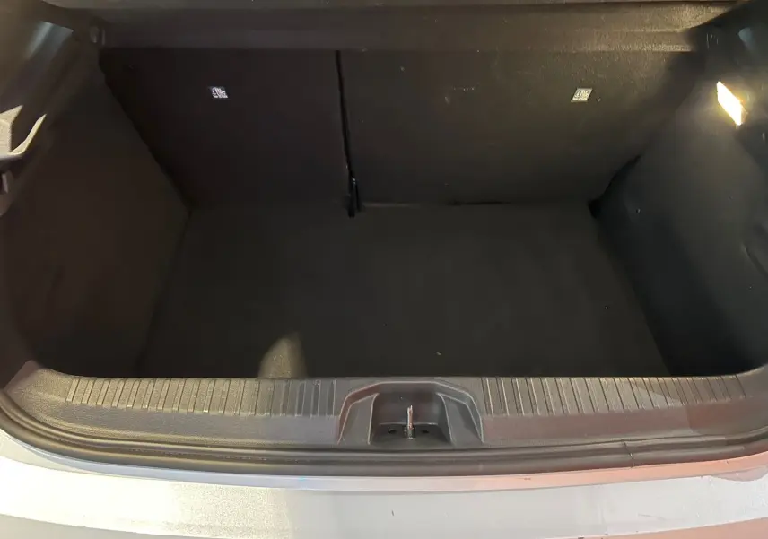 Coffre ouvert d'une Renault Clio V blanc nacré, vue plongeante sur l'espace de rangement vide.