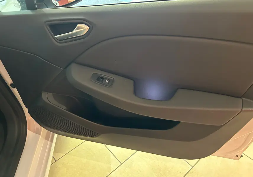 Vue rapprochée de la porte avant gauche de la Renault Clio V blanc nacré, avec poignée et commande de vitre électrique.