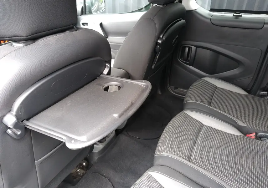 Vue intérieure côté droit du Peugeot Partner Tepee 2017, montrant la tablette rabattable sur le dossier du siège avant et les sièges tissu gris.