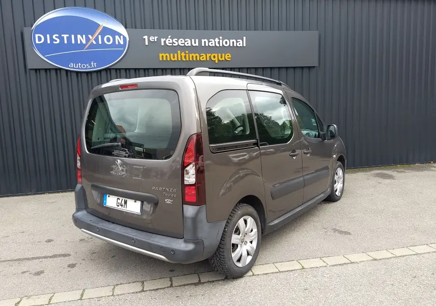 Vue 3/4 arrière droite d'un Peugeot Partner Tepee brun 2017 stationné devant un mur gris avec enseigne Distinxion.