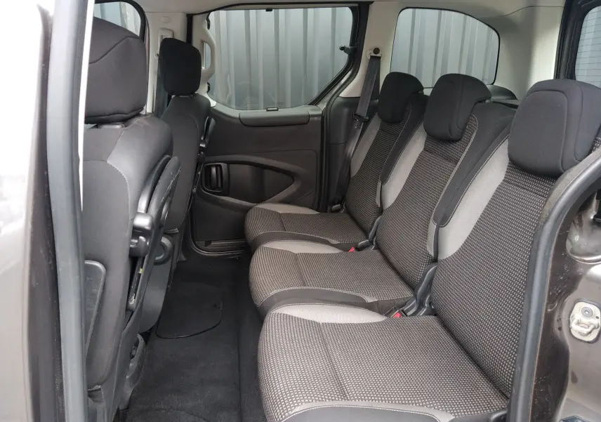 Vue intérieure côté droit des sièges arrière en tissu gris du Peugeot Partner Tepee brun, avec porte coulissante ouverte.