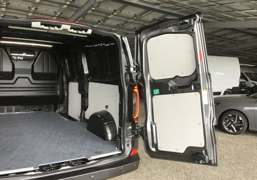 Vue arrière du Volkswagen Transporter T7 gris anthracite avec portes ouvertes dévoilant l'espace de chargement vide et les panneaux intérieurs clairs.