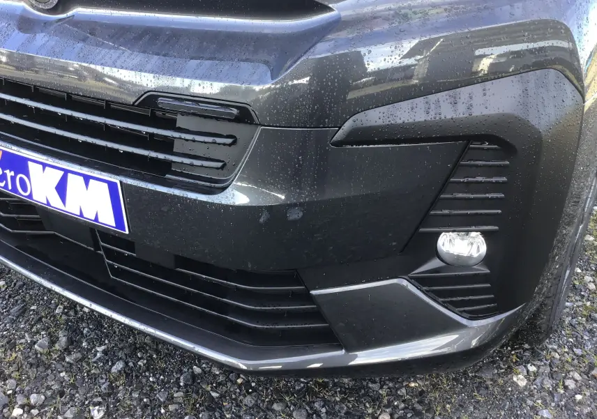 Gros plan sur l'avant droit gris titane du Citroën Jumpy XL avec calandre et antibrouillard sous la pluie.