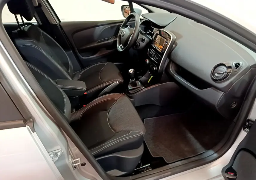 Intérieur de Renault Clio Business TCe 90 gris clair, vue côté conducteur, sièges noirs avec coutures blanches et tableau de bord moderne.