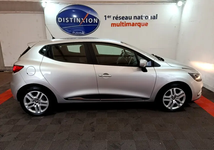 Profil côté gauche d'une Renault Clio Business TCe 90 gris clair 2019, avec jantes alliage et feux arrière allumés.