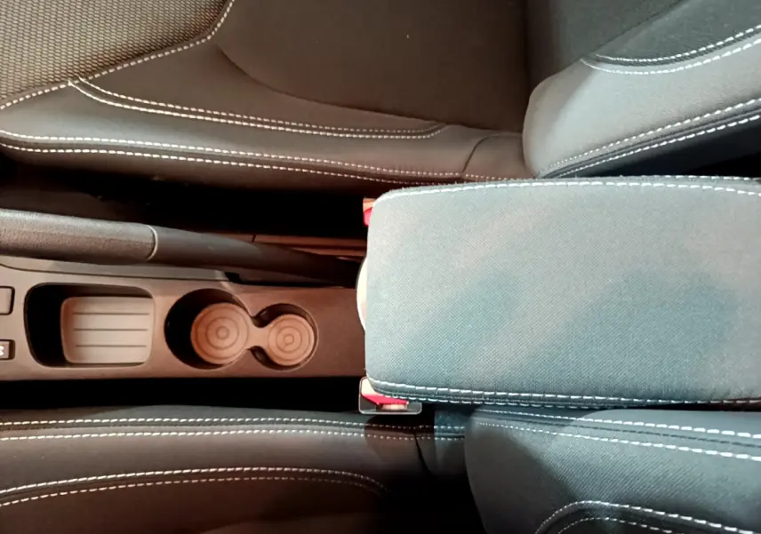 Gros plan sur l'accoudoir central et porte-gobelets entre les sièges avant gris clair de la Renault Clio Business TCe 90.