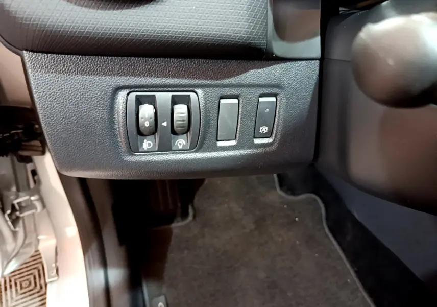 Gros plan sur les commandes de réglage des phares et antipatinage côté gauche d'une Renault Clio Business gris clair 2019.