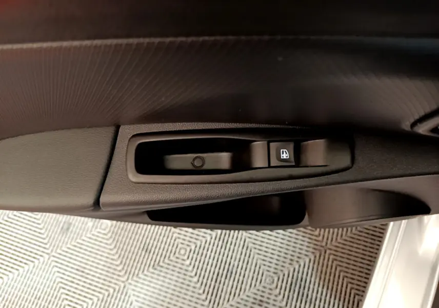 Gros plan sur la commande de lève-vitre côté conducteur d'une Renault Clio Business gris clair, intérieur noir.