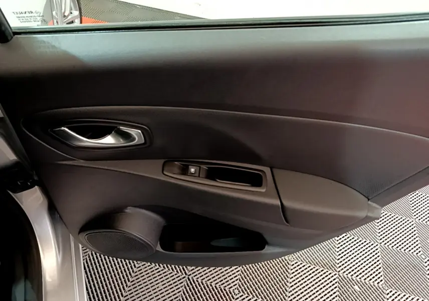 Porte côté gauche ouverte d'une Renault Clio Business TCe 90 gris clair, avec poignée intérieure et commande de vitre visible.