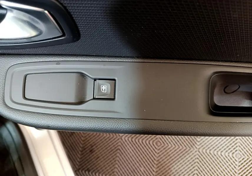 Bouton de commande de lève-vitre sur la portière côté conducteur d'une Renault Clio Business gris clair de 2019.