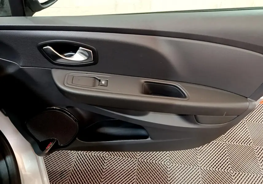 Vue rapprochée de la porte avant gauche d'une Renault Clio Business gris clair, avec poignée et commande de vitre.