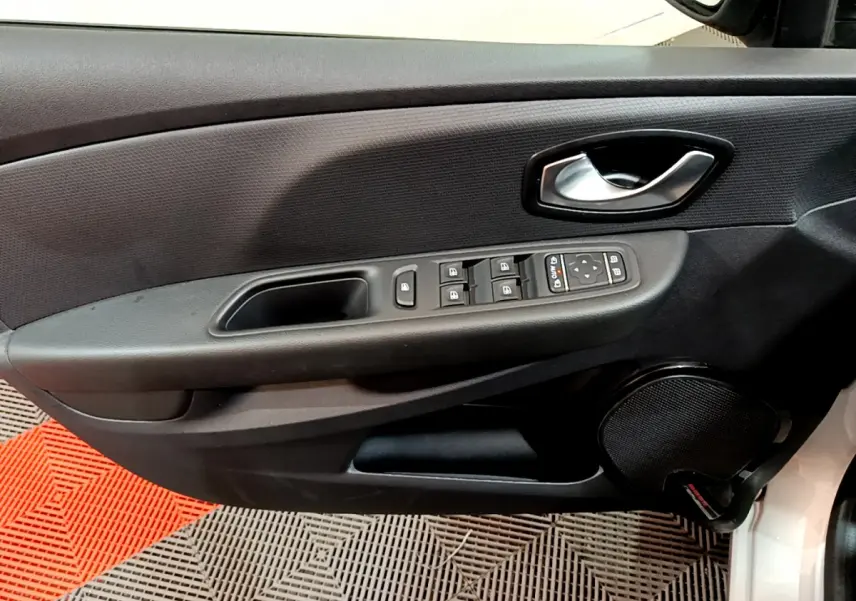 Vue rapprochée de la porte avant gauche d'une Renault Clio Business gris clair, avec commandes électriques et haut-parleur intégré.