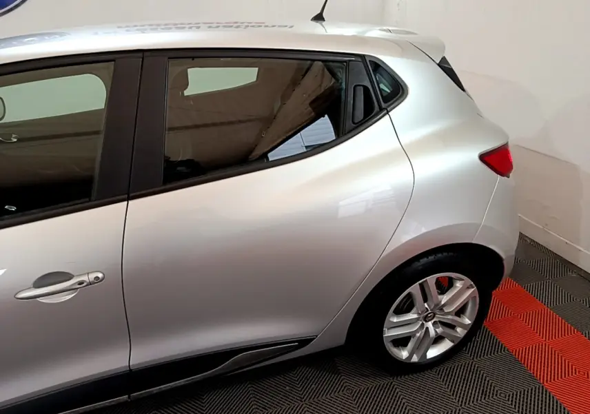 Vue latérale côté gauche d'une Renault Clio Business TCe 90 gris clair, avec jante alliage et poignée de porte visible.