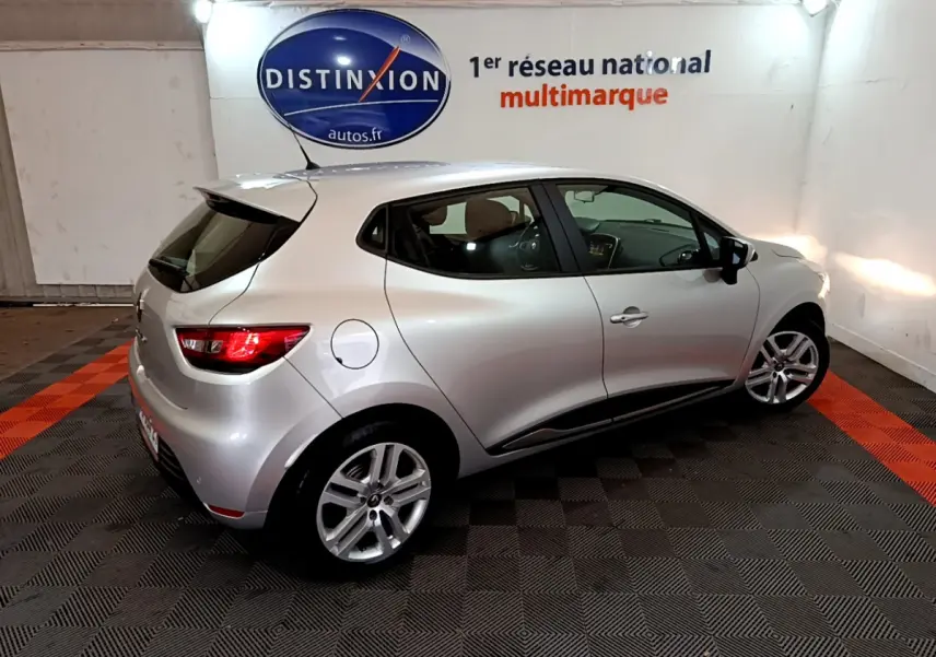 Renault Clio Business TCe 90 gris clair vue 3/4 arrière droit en intérieur avec feux arrière allumés