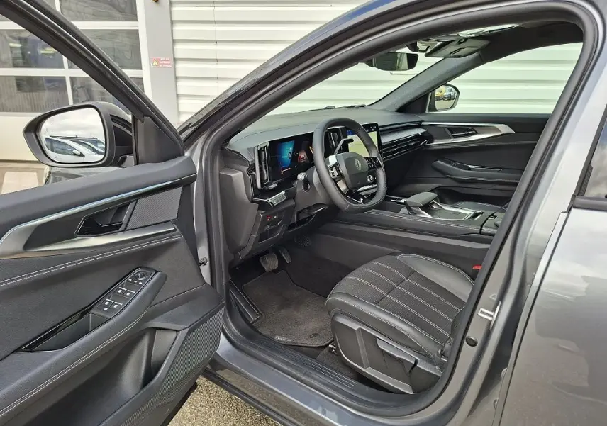 Vue intérieure côté conducteur de la Renault Austral gris schiste 2025, mettant en valeur le tableau de bord digital et les sièges en tissu.