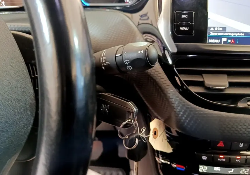 Détail intérieur du volant cuir et tableau de bord tactile du Peugeot 2008 Diesel, avec clé insérée et commandes visibles.