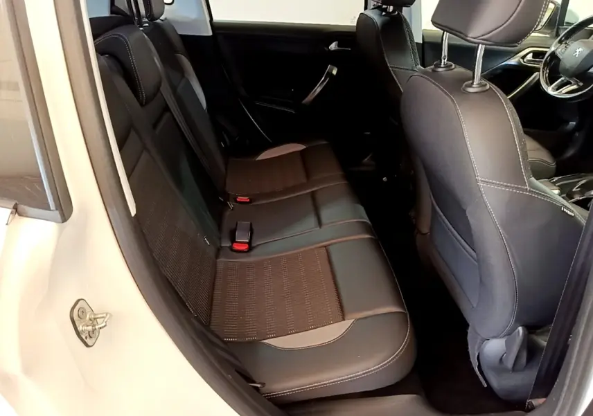 Vue intérieure côté gauche montrant la banquette arrière noire et les sièges avant d'une Peugeot 2008 blanche.
