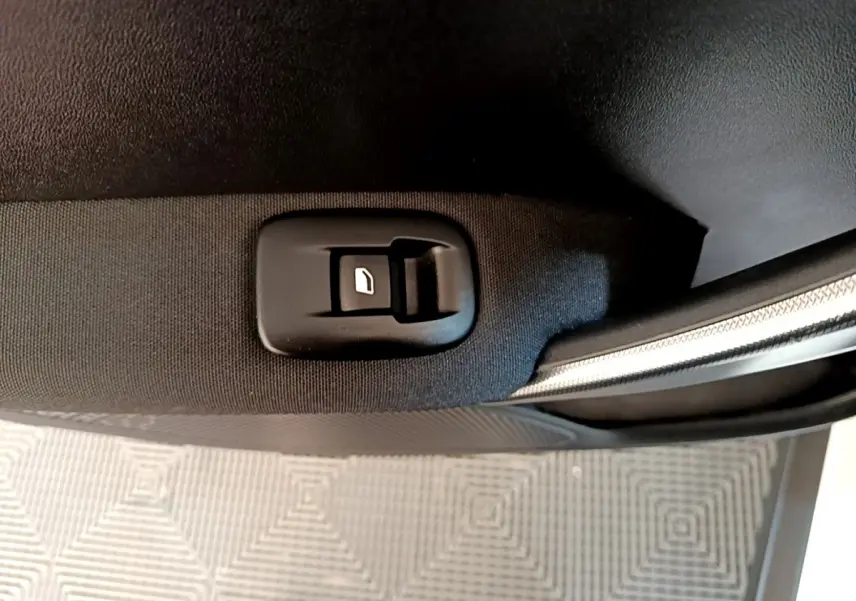 Gros plan sur le bouton de verrouillage de porte côté intérieur d'une Peugeot 2008 2019, tissu noir et garniture argentée.