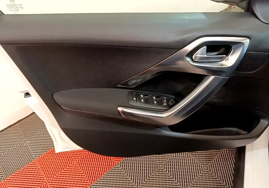 Vue intérieure de la porte avant gauche noire d'un Peugeot 2008 2019, avec commandes de vitres et poignée argentée.
