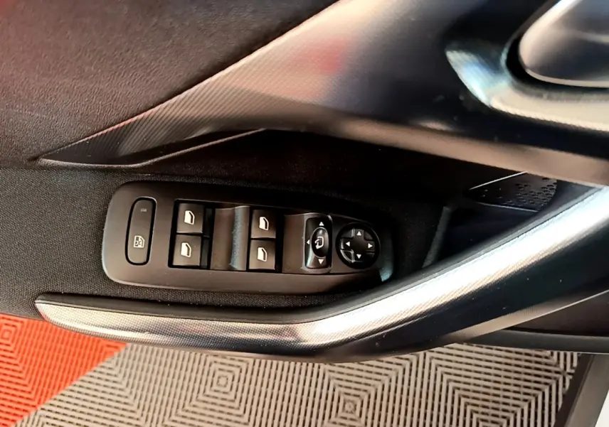 Vue rapprochée de la commande des vitres électriques côté conducteur d’un Peugeot 2008, avec poignée argentée et garniture noire.