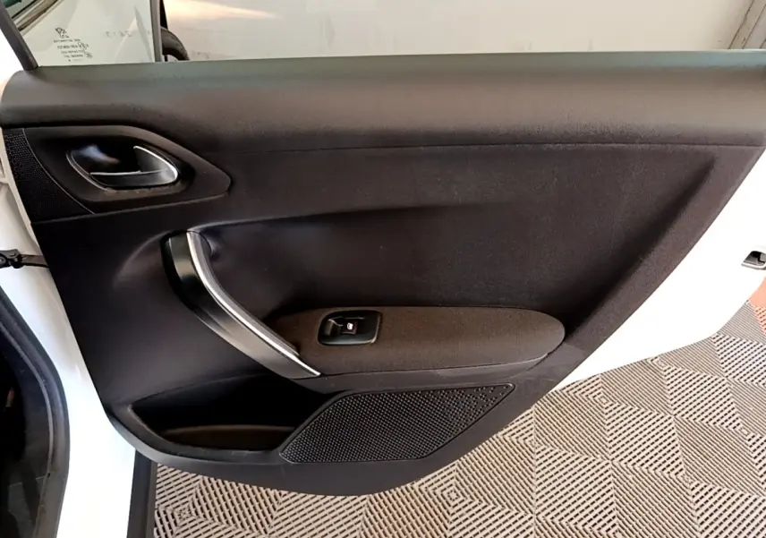Vue intérieure de la porte arrière gauche noire du Peugeot 2008, avec poignée argentée et bouton de lève-vitre.