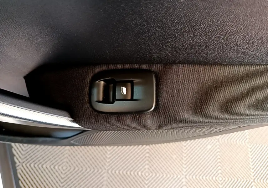 Gros plan sur le bouton de lève-vitre arrière droit en tissu noir dans une Peugeot 2008 BlueHDi 2019.